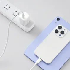 Biały telefon i tablet ładują się przez kabel. Wtyczka zasilająca jest podłączona do listwy zasilającej. ESD.