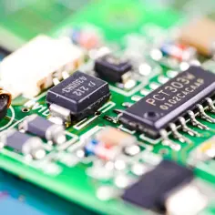 Zbliżenie na zieloną płytkę drukowaną z widocznym układem scalonym PCT303W, cewką i innymi komponentami elektronicznymi.