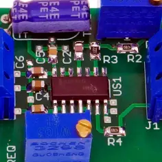 Płytka drukowana z elementami elektronicznymi, w tym kondensatorami, rezystorami i układem scalonym. Widoczne złącza śrubowe GND i OUT, potencjometr oraz oznaczenia elementów. To serce impulsatora.