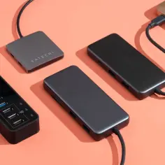 Czarny hub z wieloma portami USB i dwa szare huby Satechi, jeden podłączony do laptopa.