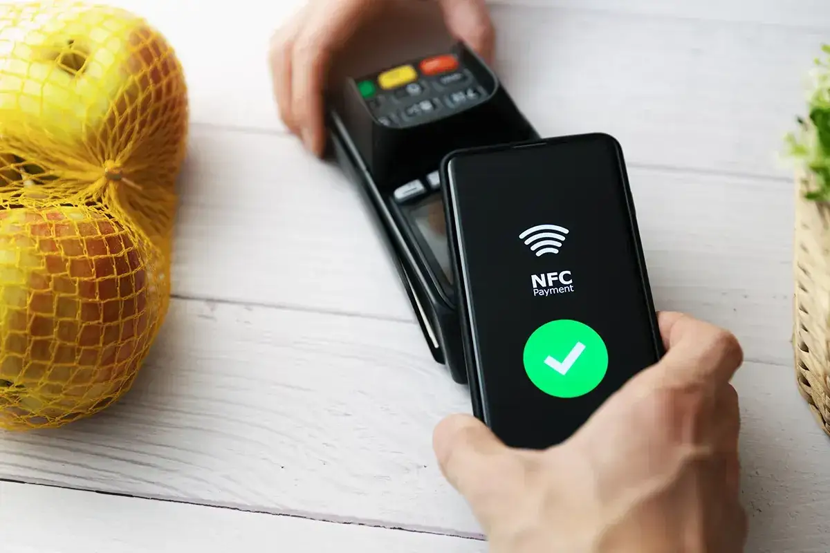Płatność zbliżeniowa telefonem. Widzisz symbol NFC i zielony znaczek potwierdzenia. To właśnie NFC, co to jest – szybki sposób płacenia.